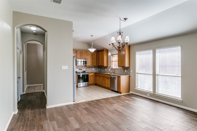 kitchen with sink, a notable chandelier, decorative light fixtures, lofted ceiling, and appliances with stainless steel finishes