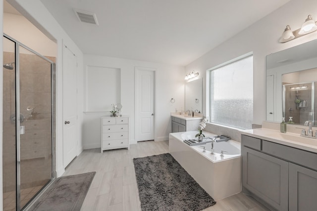 bathroom with vanity and shower with separate bathtub