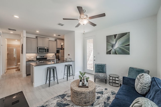 living room featuring ceiling fan, light hardwood / wood-style floors, and sink