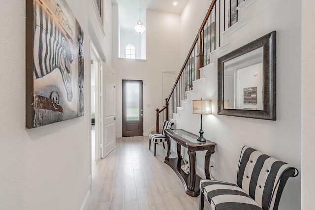 foyer entrance featuring light wood-type flooring, a towering ceiling, and a wealth of natural light