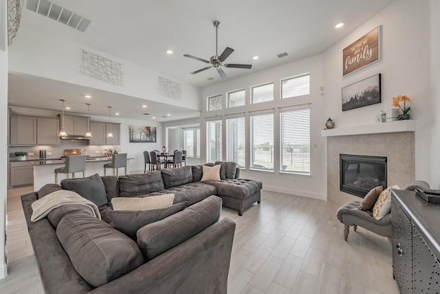 living room featuring a tile fireplace and ceiling fan