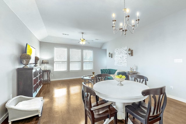 dining space featuring ceiling fan with notable chandelier, dark wood-type flooring, and lofted ceiling