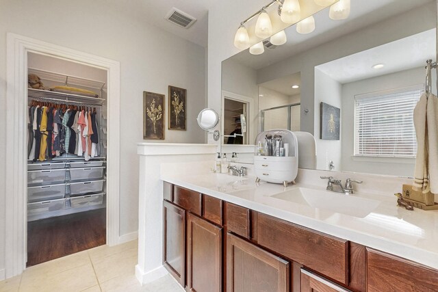 bathroom with tile patterned flooring, vanity, and a shower with door