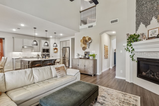 living room featuring sink, dark hardwood / wood-style flooring, a high ceiling, and a tile fireplace