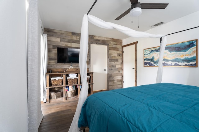 bedroom with ceiling fan, wood-type flooring, and wood walls