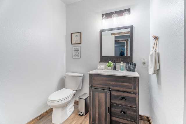 bathroom with hardwood / wood-style floors, vanity, and toilet