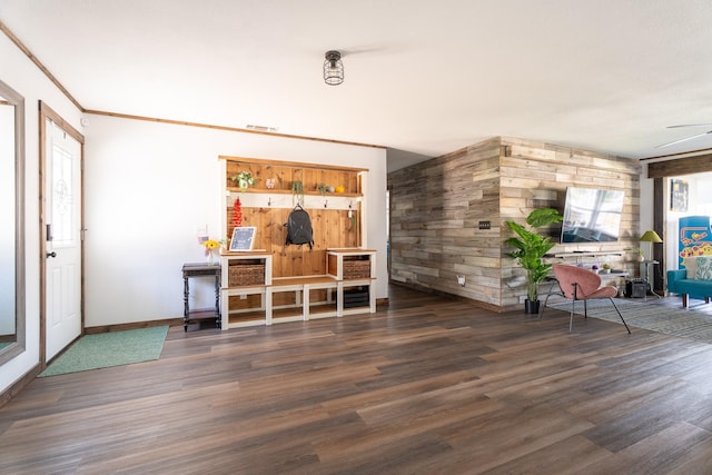 living room with ceiling fan, wood walls, dark hardwood / wood-style flooring, and crown molding