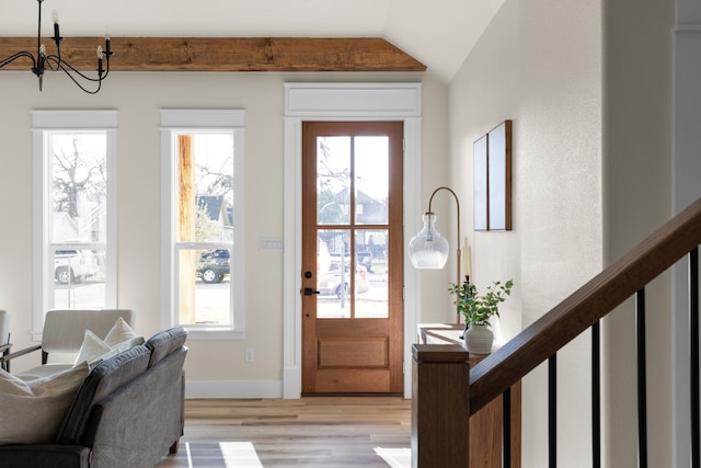 doorway to outside featuring a notable chandelier, lofted ceiling, and light wood-type flooring