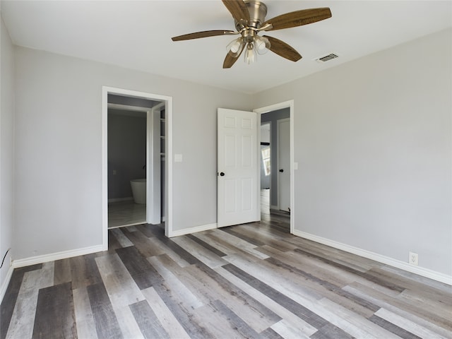 unfurnished bedroom featuring dark hardwood / wood-style flooring, ensuite bath, and ceiling fan