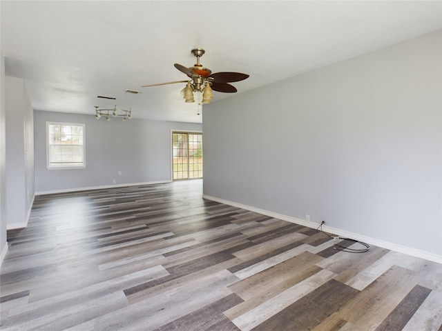 spare room featuring dark wood-type flooring, ceiling fan, and a wealth of natural light