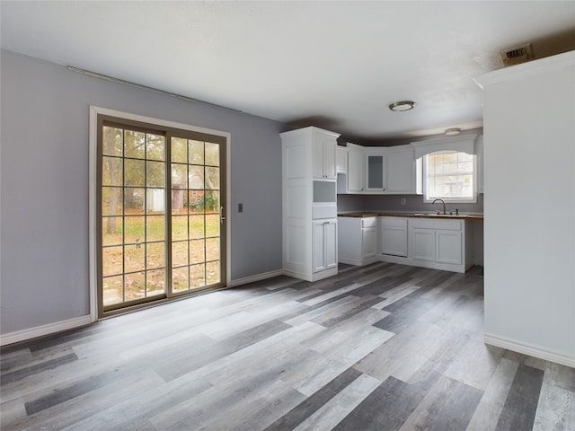 kitchen with white cabinets, sink, and light hardwood / wood-style flooring