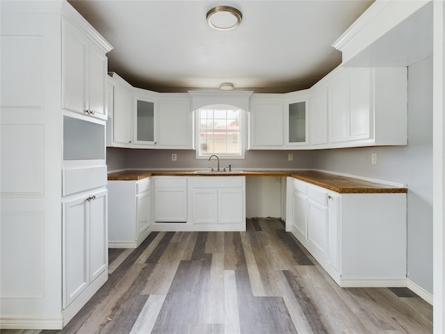 kitchen with white cabinets, sink, and light hardwood / wood-style flooring