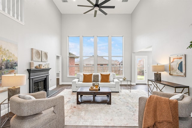 living room with a towering ceiling, dark hardwood / wood-style flooring, and ceiling fan