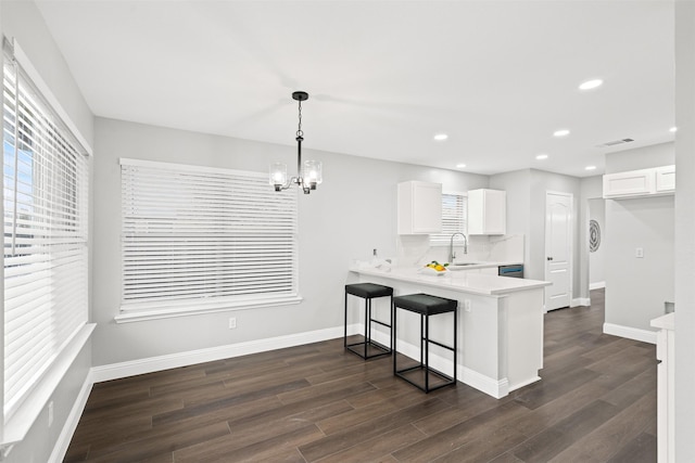 kitchen with pendant lighting, a breakfast bar, kitchen peninsula, sink, and white cabinetry