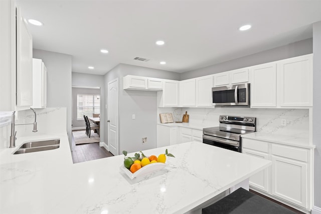 kitchen featuring kitchen peninsula, white cabinetry, sink, and appliances with stainless steel finishes