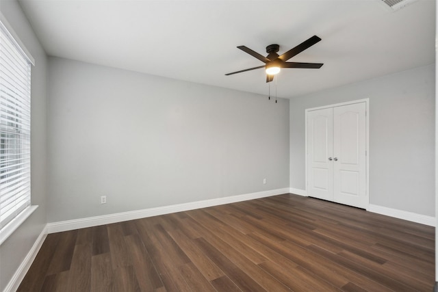 unfurnished bedroom with ceiling fan, dark hardwood / wood-style floors, and a closet