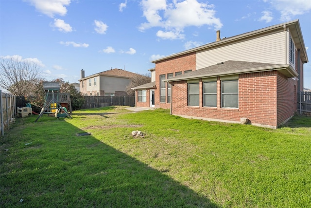 back of house with a playground and a lawn