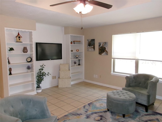 living area featuring built in shelves, ceiling fan, and light tile patterned flooring