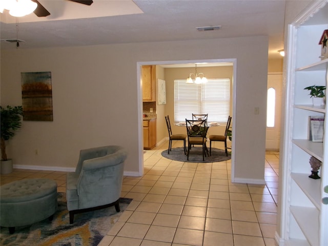 living room with light tile patterned flooring and ceiling fan with notable chandelier