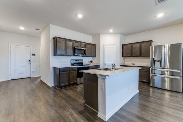 kitchen with dark brown cabinetry, stainless steel appliances, sink, dark hardwood / wood-style floors, and an island with sink