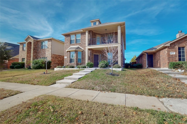 view of front of home with brick siding, a balcony, and a front lawn