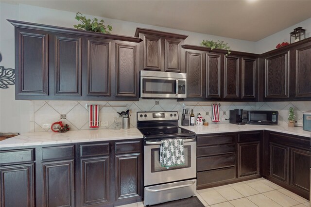 kitchen with backsplash, dark brown cabinets, and stainless steel appliances