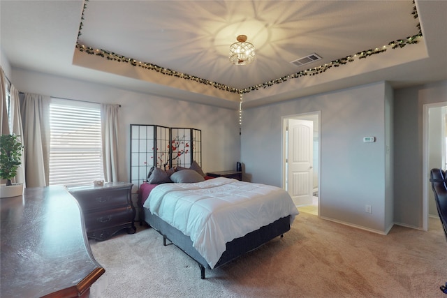 bedroom featuring a raised ceiling and light colored carpet