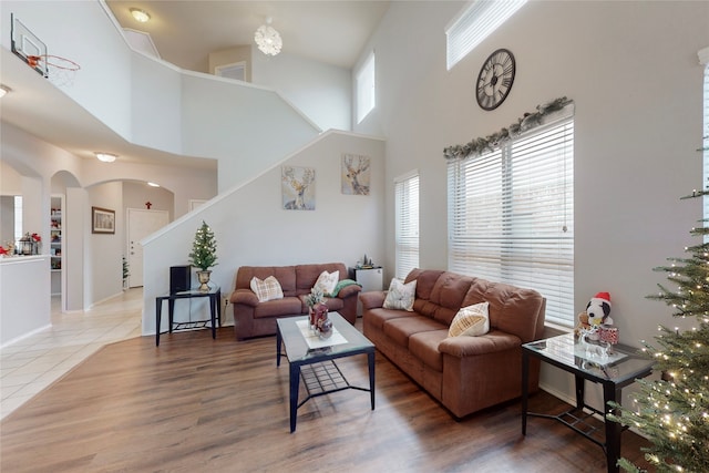 living room featuring arched walkways, wood finished floors, and stairs