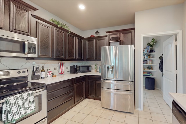 kitchen with light tile patterned floors, decorative backsplash, dark brown cabinets, and stainless steel appliances