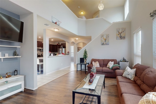 living room featuring a towering ceiling and wood-type flooring