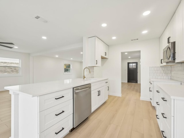 kitchen with light countertops, visible vents, appliances with stainless steel finishes, white cabinetry, and a sink