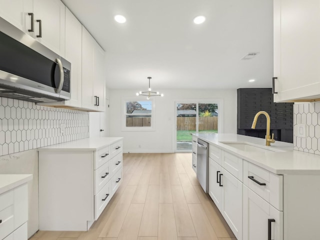 kitchen with stainless steel appliances, light countertops, and white cabinets