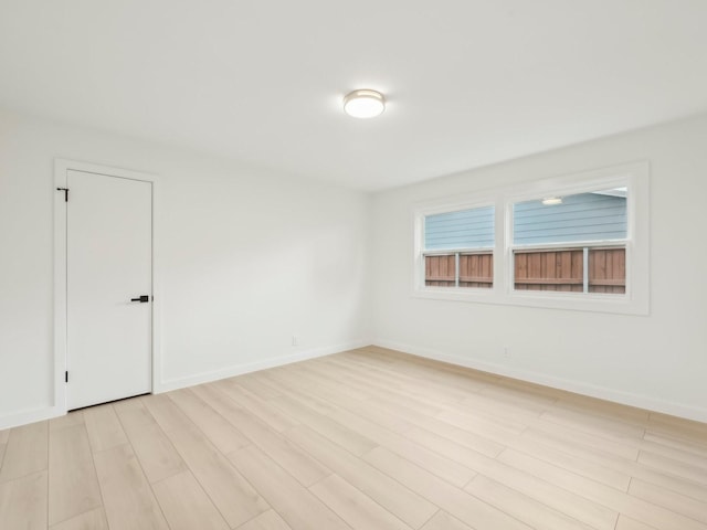 spare room featuring light wood-type flooring and baseboards