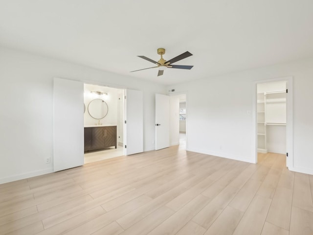 unfurnished bedroom with light wood-style floors, a spacious closet, and baseboards