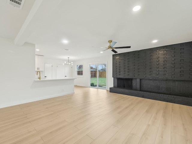 unfurnished living room featuring recessed lighting, light wood-style flooring, visible vents, and ceiling fan with notable chandelier