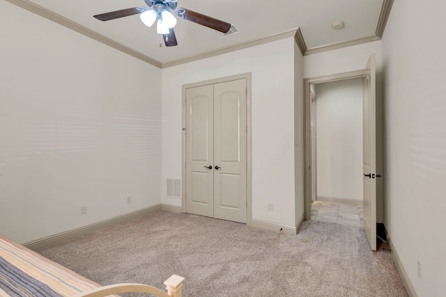 unfurnished bedroom featuring crown molding, ceiling fan, a closet, and light carpet