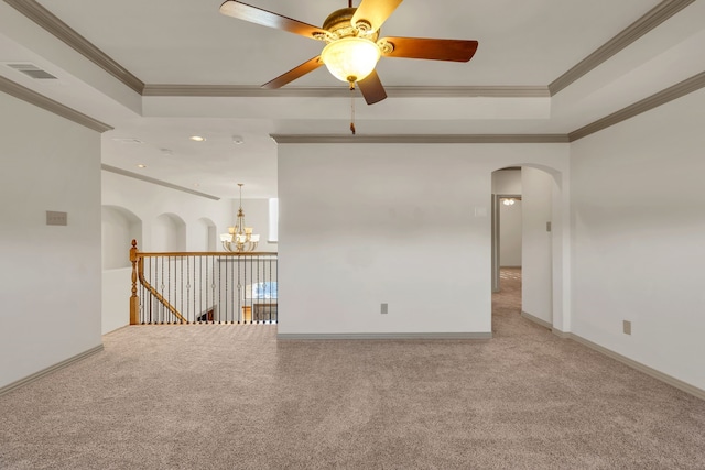 carpeted empty room with a raised ceiling, crown molding, and ceiling fan with notable chandelier