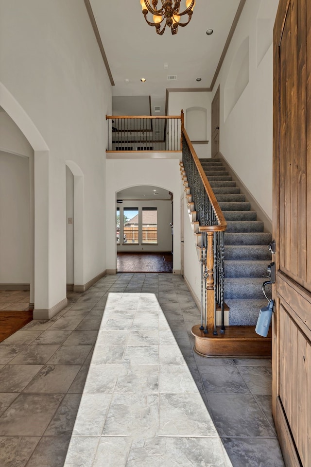 foyer entrance with a high ceiling, crown molding, and an inviting chandelier