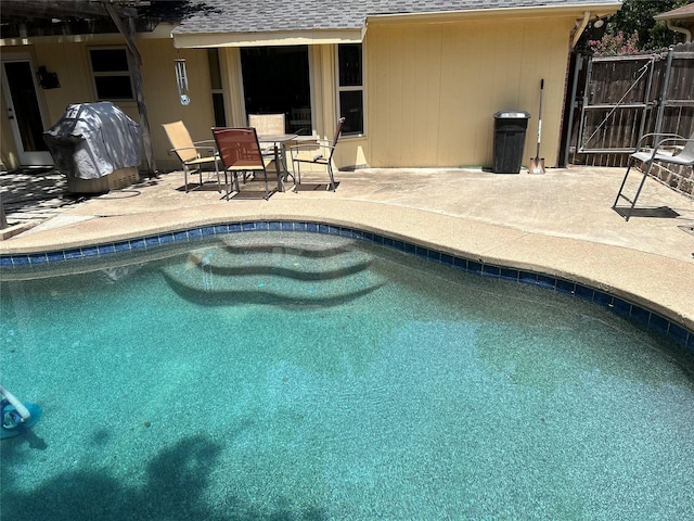 outdoor pool with area for grilling, a patio area, and a gate