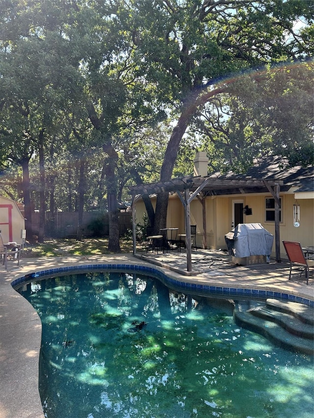 outdoor pool with a patio area, a grill, and fence