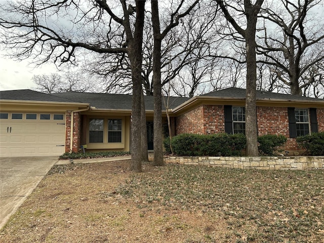 single story home with concrete driveway, brick siding, and an attached garage