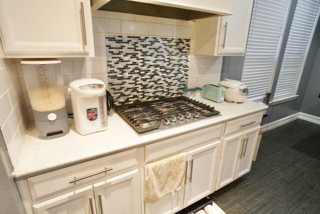 kitchen featuring stainless steel gas stovetop, dark hardwood / wood-style floors, decorative backsplash, and range hood