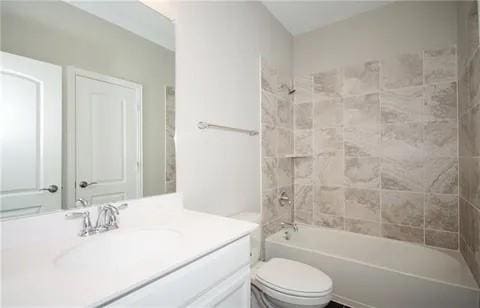 full bathroom featuring vanity, tiled shower / bath, and toilet