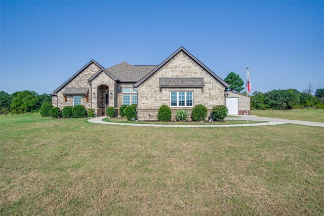 french country home featuring a front lawn and a garage