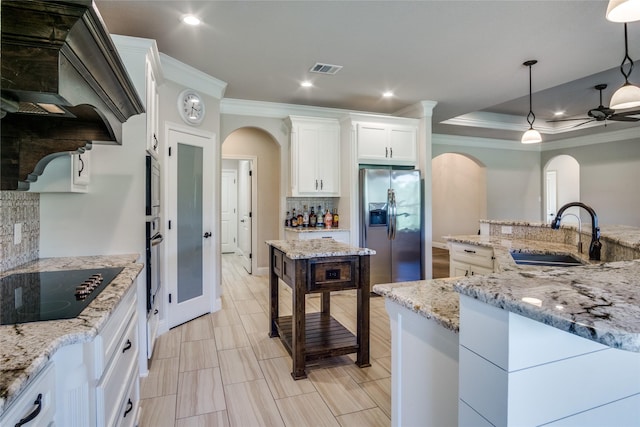 kitchen with premium range hood, sink, white cabinetry, hanging light fixtures, and stainless steel appliances