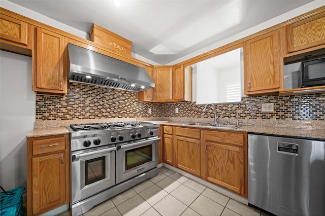 kitchen with light stone countertops, sink, wall chimney exhaust hood, decorative backsplash, and appliances with stainless steel finishes