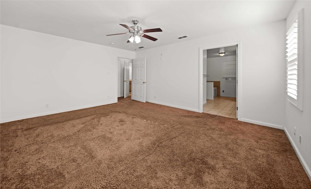 unfurnished bedroom featuring light colored carpet, ensuite bath, and ceiling fan