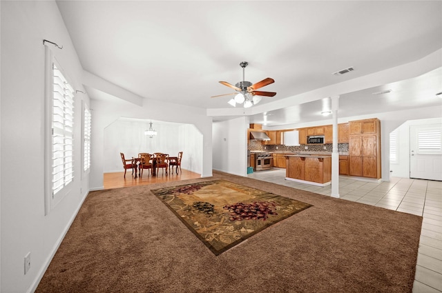 tiled living room with ceiling fan with notable chandelier