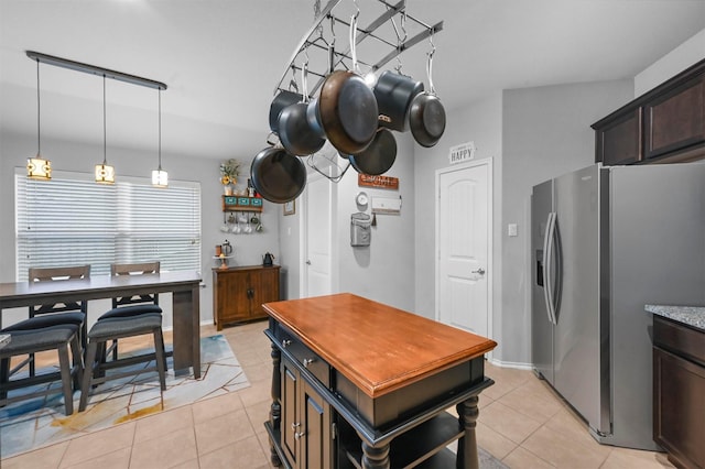 kitchen with hanging light fixtures, light tile patterned floors, dark brown cabinetry, and stainless steel fridge with ice dispenser