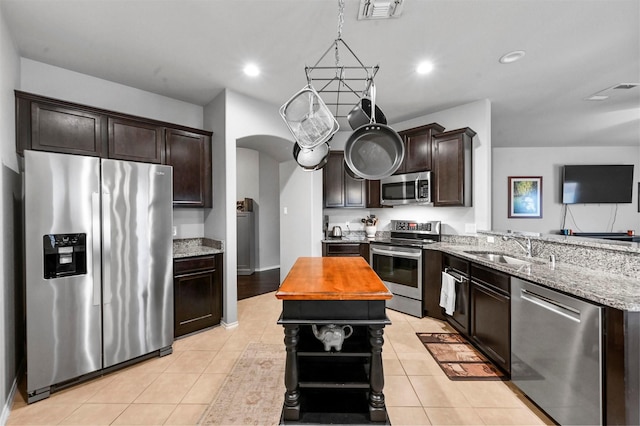 kitchen featuring light tile patterned flooring, appliances with stainless steel finishes, sink, and dark brown cabinetry